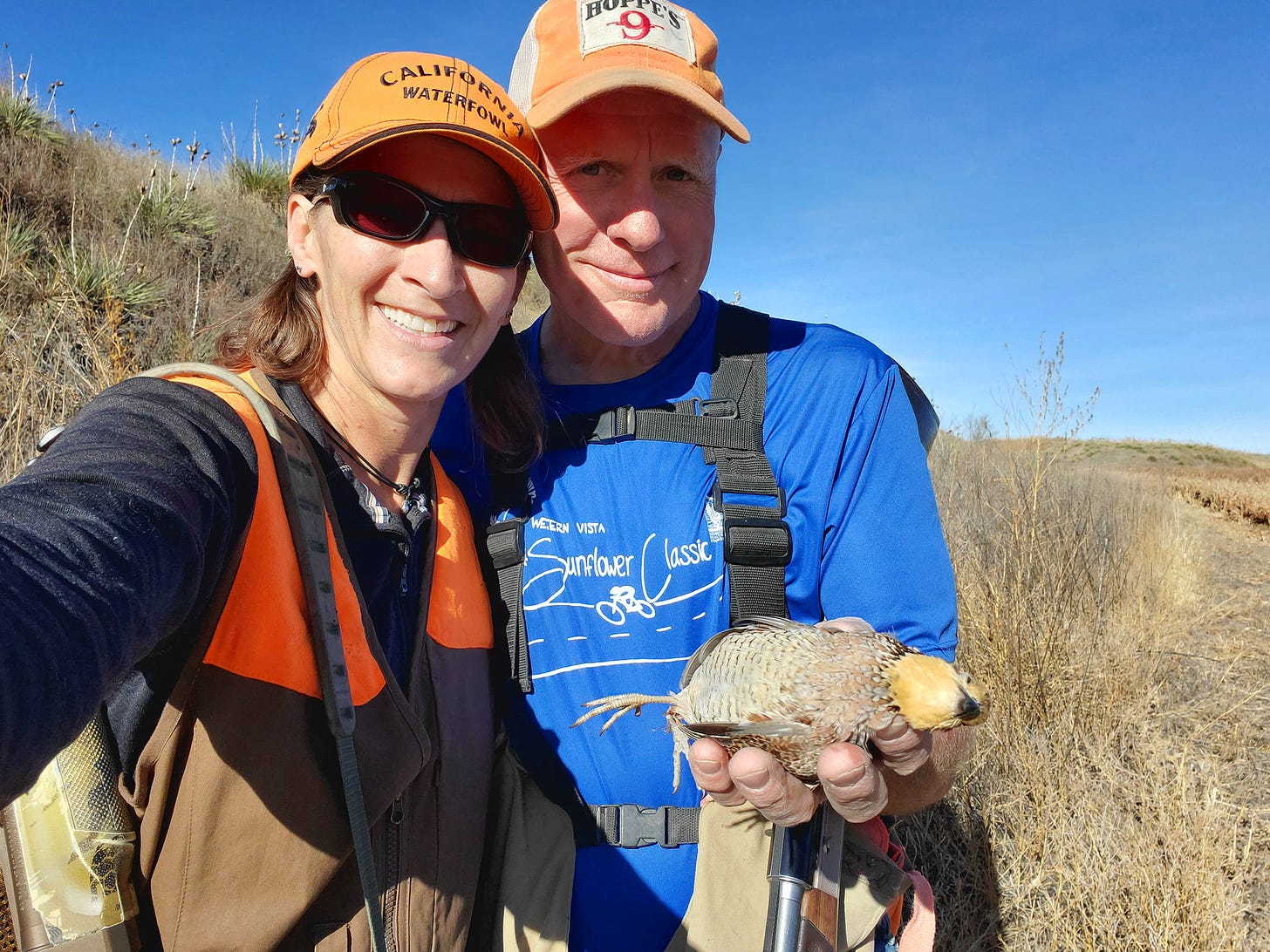 Two hunters holding a quail
