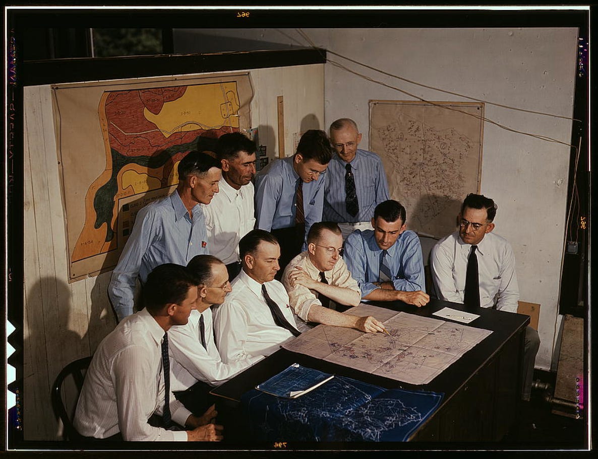 a bunch of white men in ties around a table, likely mid century