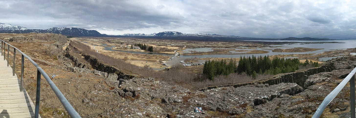 Panoramic photo from the lookout over Thingvellir, Iceland, showing mountains in the background and the meeting grounds dating from the year 950 in the valley immediately below the viewer.