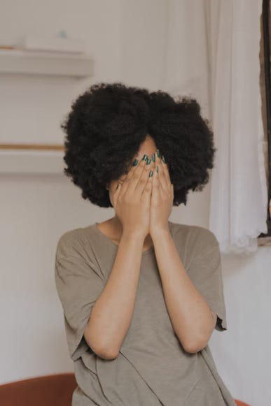 A person hides their face in their hands. From Unsplash.