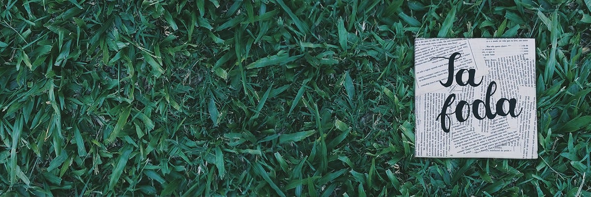 Fundo com grama verde e um papel recordado escrito "Tá foda"