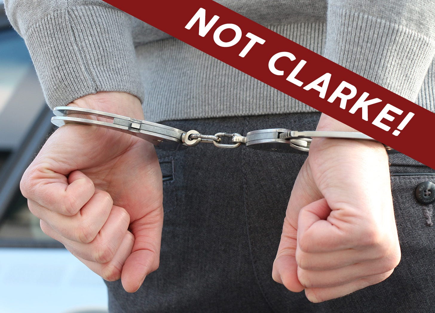 Close up of hands cuffed behind back. Text on top reads "Not Clarke!"