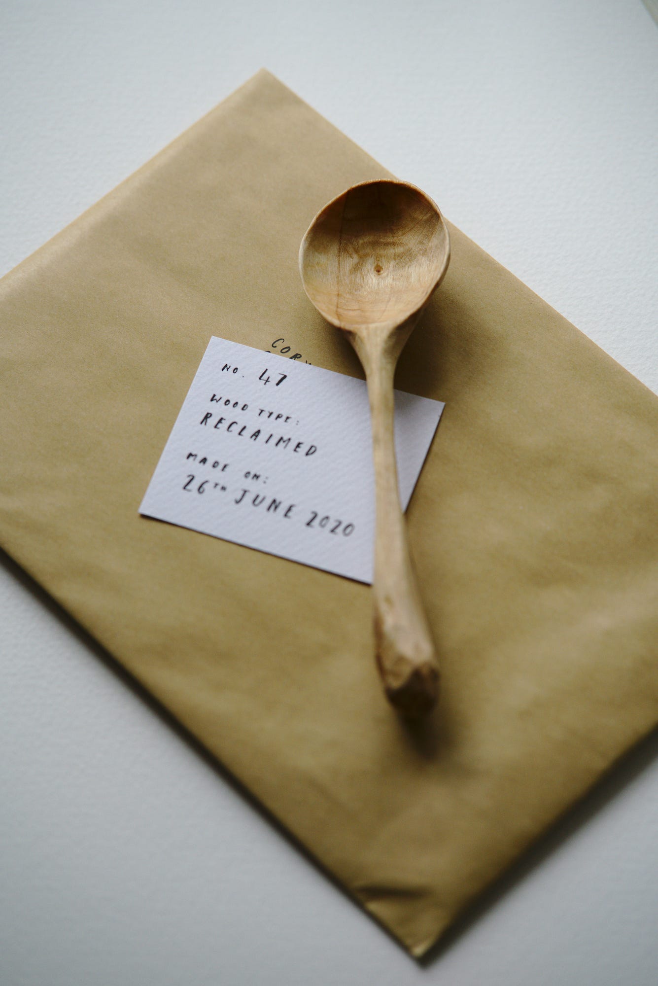 A hand written card sitting next to the spoon that was our first official online order, telling about the wood type, when it was made, etc.