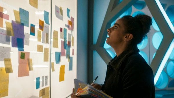 This image shows Yasmin "Yaz" Khan (played by Mandip Gill) standing inside the spare TARDIS that the Thirteenth Doctor salvaged at the end of Doctor Who's Series 12 finale ("The Timeless Children"). Yaz stares at a wall of clippings and stick-it notes that include clues to her search for the Doctor. This image shows Yasmin "Yaz" Khan (played by Mandip Gill) standing inside the spare TARDIS that the Thirteenth Doctor salvaged at the end of Doctor Who's Series 12 finale ("The Timeless Children"). Yaz stares at a wall of clippings and stick-it notes that include clues to her search for the Doctor.