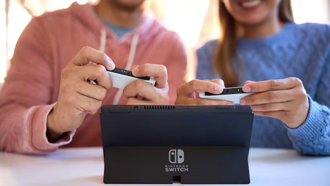 Two people playing a Nintendo Switch OLED