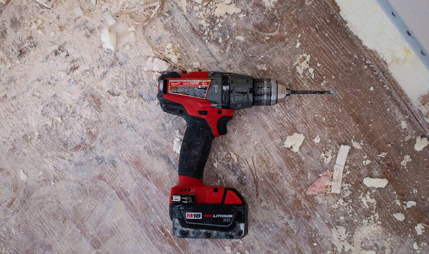 A handheld cordless electric drill on the ground of a construction site