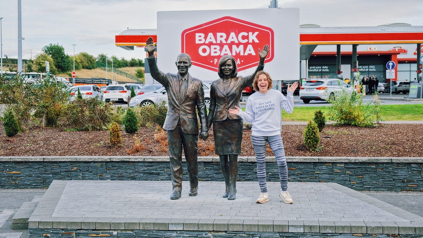 Leah with statues of Barack and Michelle Obama at the Barack Obama Plaza Gas Station.