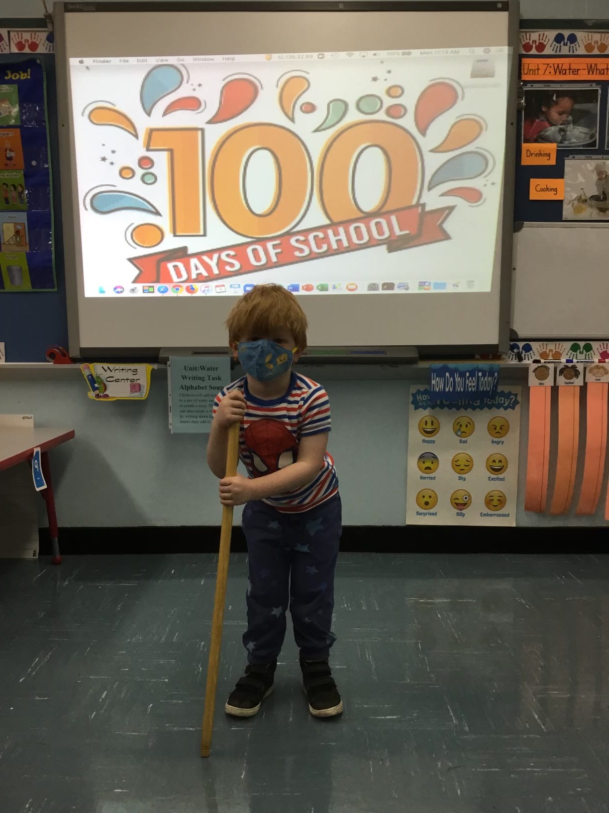 A youung boy stands with a cane in front of a one-hundred days of school banner"