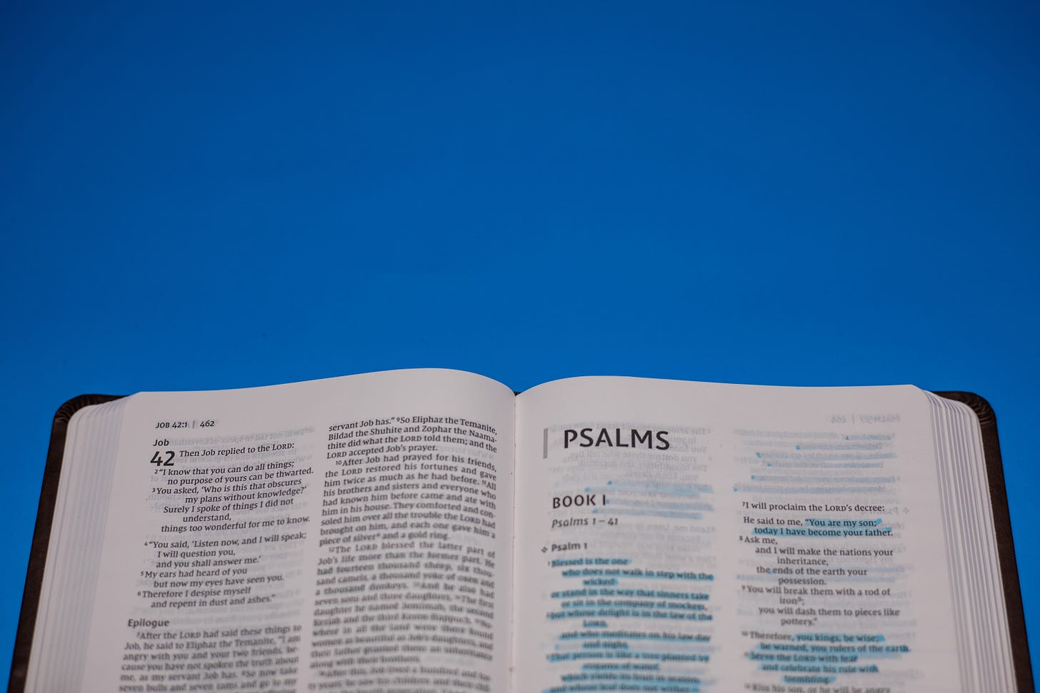 The Bible opened to Psalm 1 against a blue background. 
