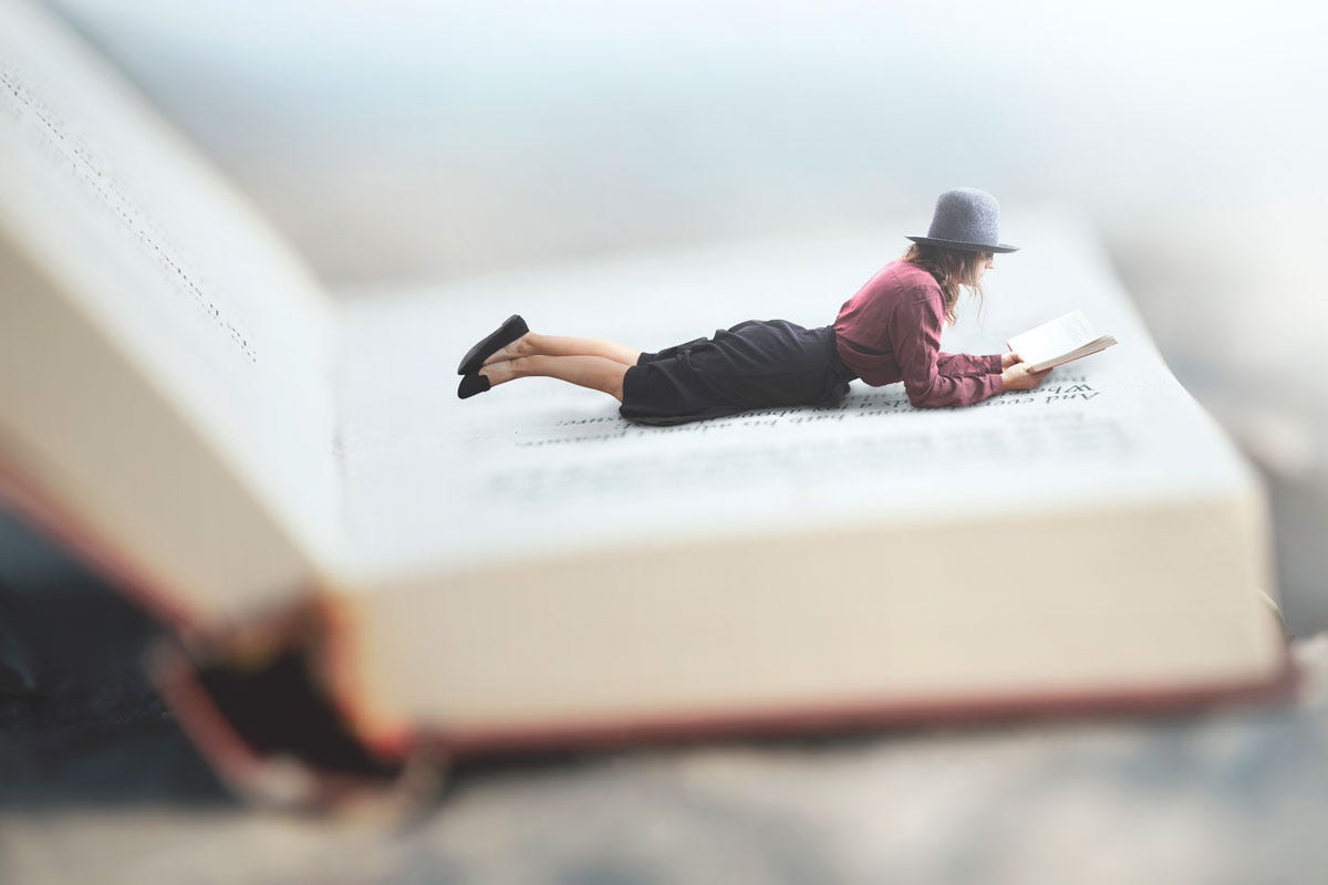 Woman Reading Book While Lying on Giant Book