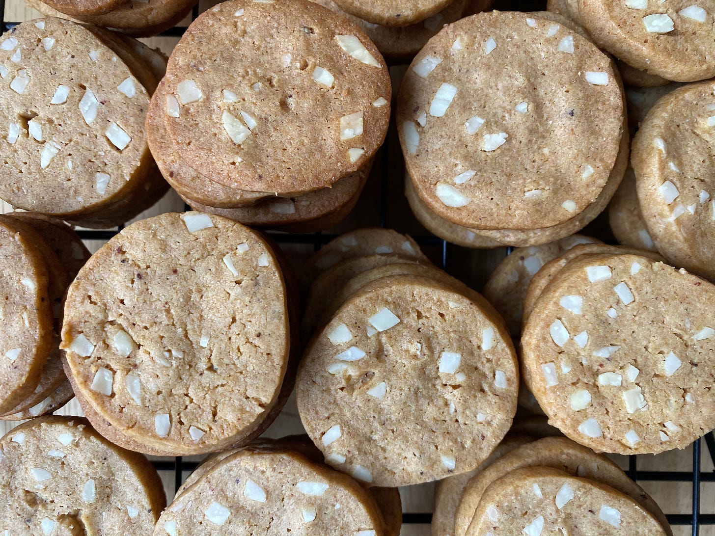 Stacks of small round cookies, lightly brown and studded with almonds.