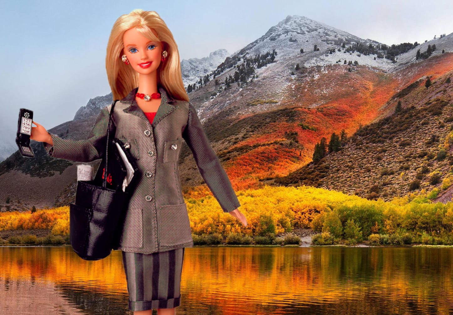 A fair skinned, blonde haired and blue eyed Barbie wears a grey skirt suit while holding a large purse and flip phone. Behind her is an expansive snowy mountain range with orange and yellow fall foliage.
