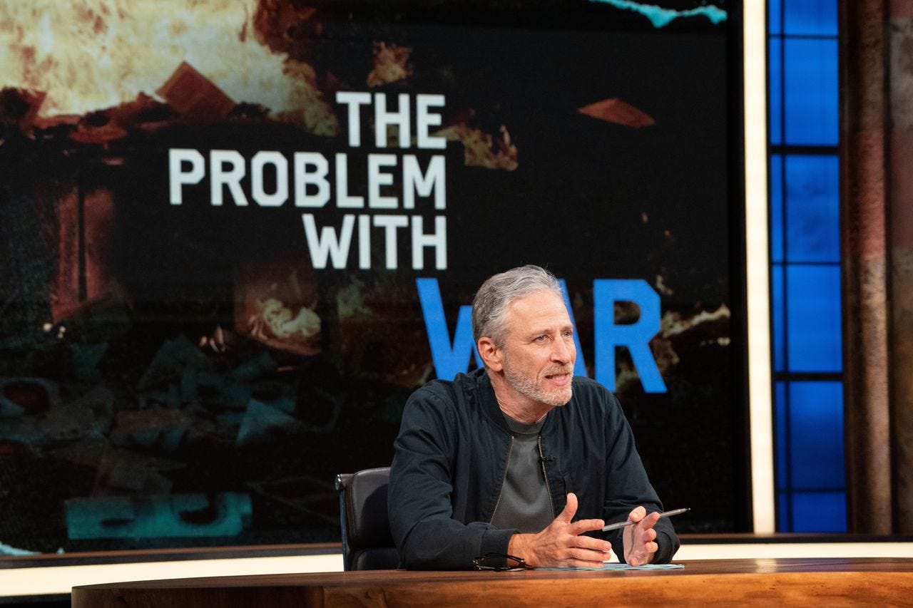 Jon Stewart sits at a table during the first episode of the show The Problem With Jon Stewart