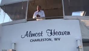 Boat named "Almost Heaven" with man looking out the window.