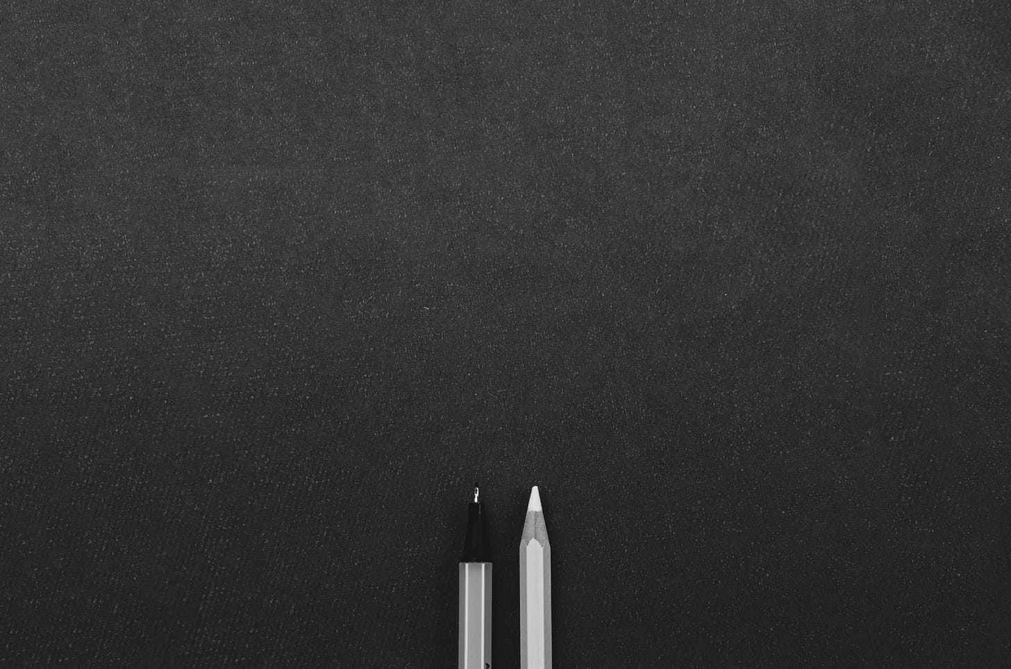 Two pens on a black surface.
