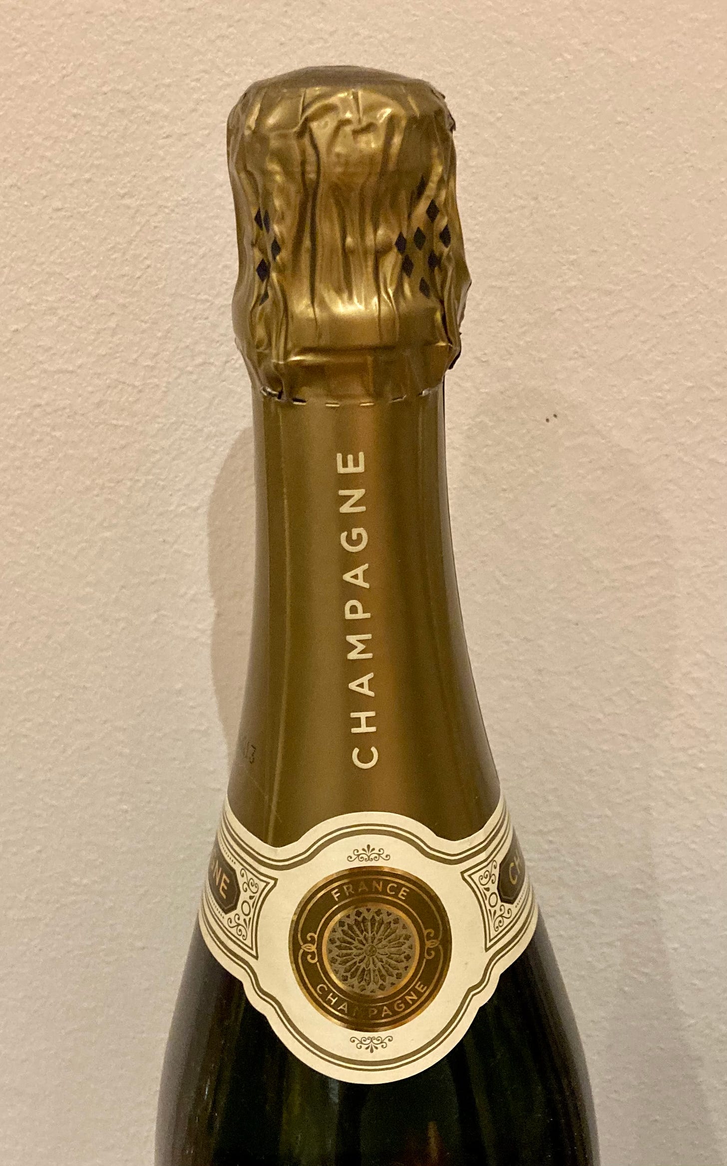 A champagne bottle with a large capsule used for branding.