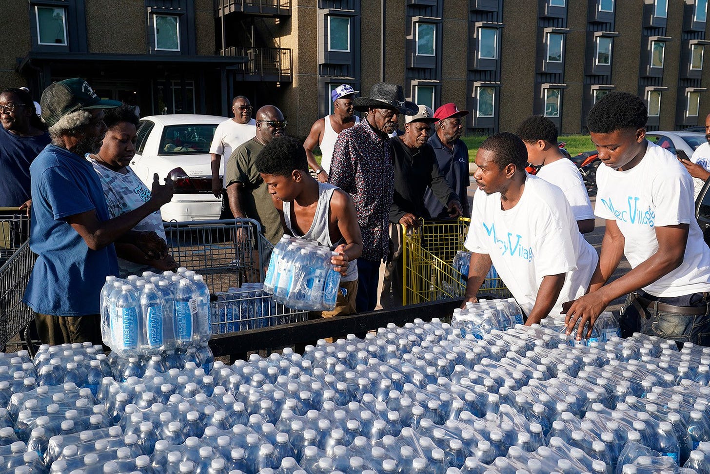 A group of Black people outside handing out cases of water to residents