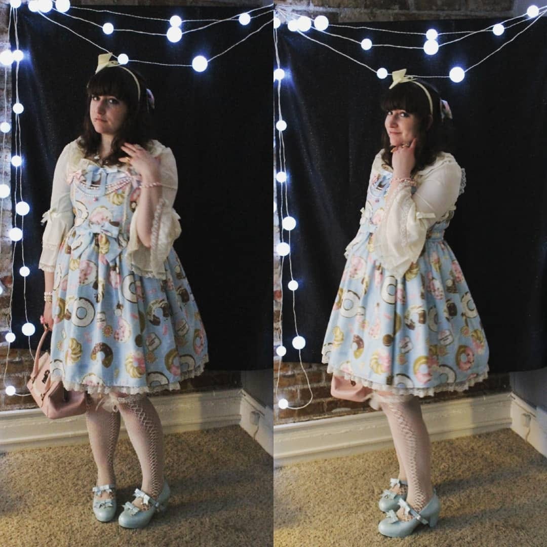 Nif (a white woman with dark brown hair) wearing a coord with Angelic Pretty's Baked Sweets Parade in sax. She is wearing an ivory headbow, ivory hime-sleeve blouse, and ivory fishnets, sax shoes with bows, and holding a pink BTSSB crown bag. She is wearing a pearly collar pin and several bracelets. She is standing in front of a black background with lit string lights. The coord is pictured at 2 slightly different angles. Nif's socks are slightly crooked.