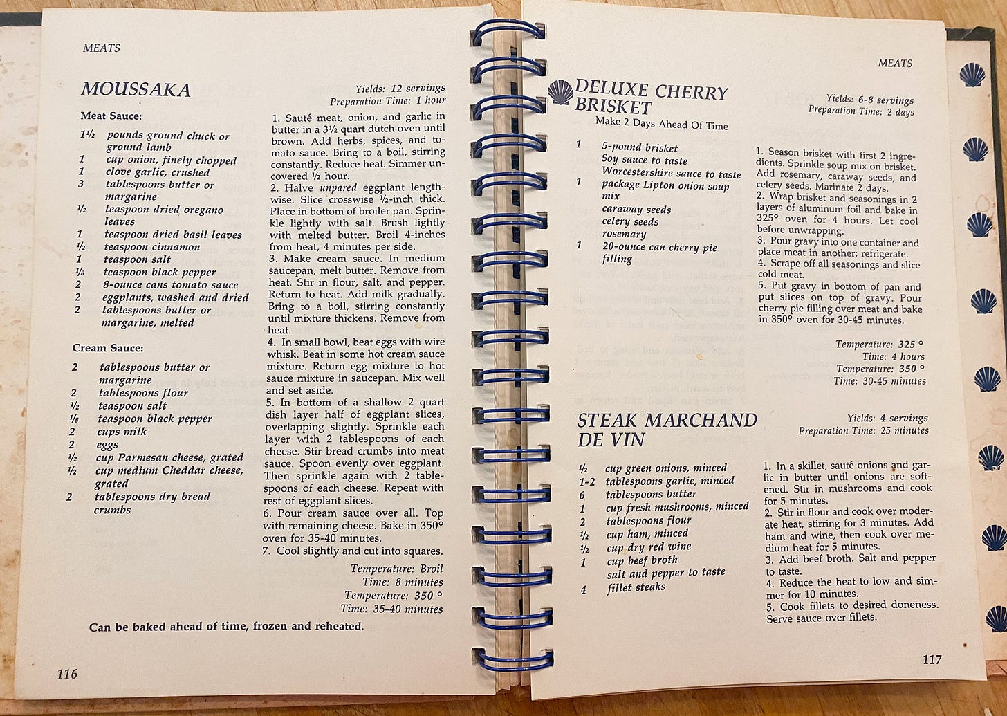 photo of a two-page cookbook spread, with recipes for moussaka, deluxe cherry brisket, and steak marchand de vin