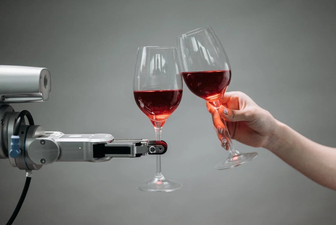 robot arm and human arm both holding wine, clinking glasses