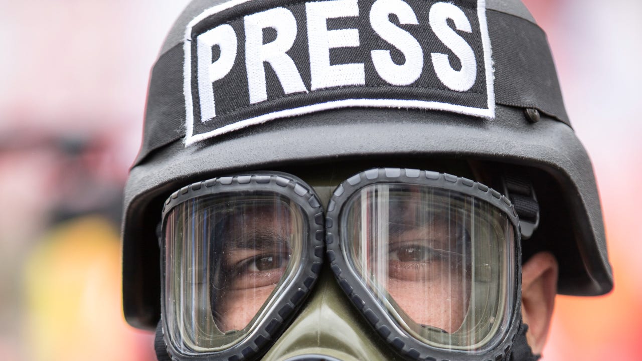 Man wearing a gas mask and "Press" helmet
