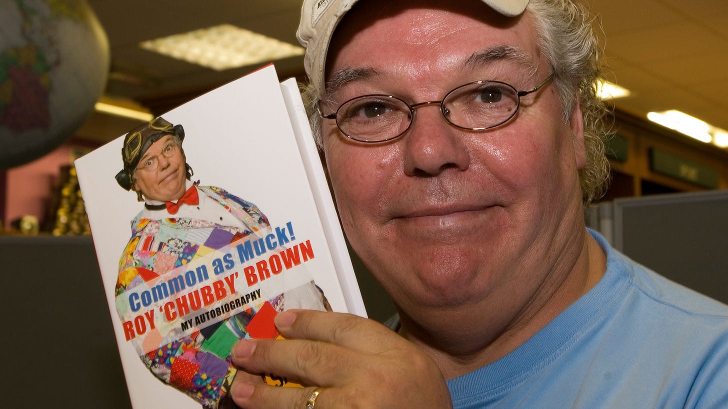 Comedian Roy 'Chubby' Brown holds up a copy of his autobiography Common As Muck.