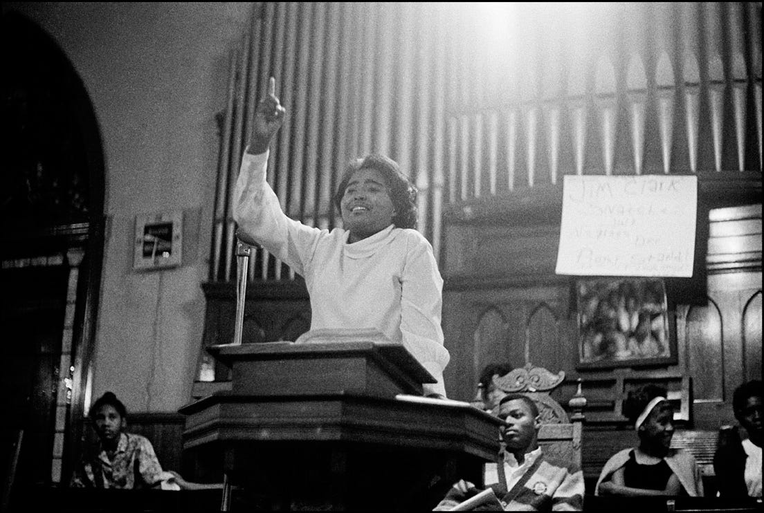 Black and white photo of Parthia Hall in white garments preaching with upraised hand and pointed finger