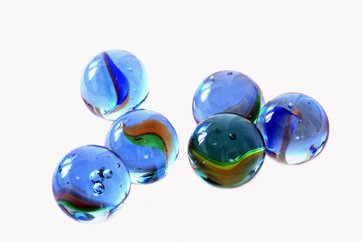 Six blue marbles are shown close-up against a white background
