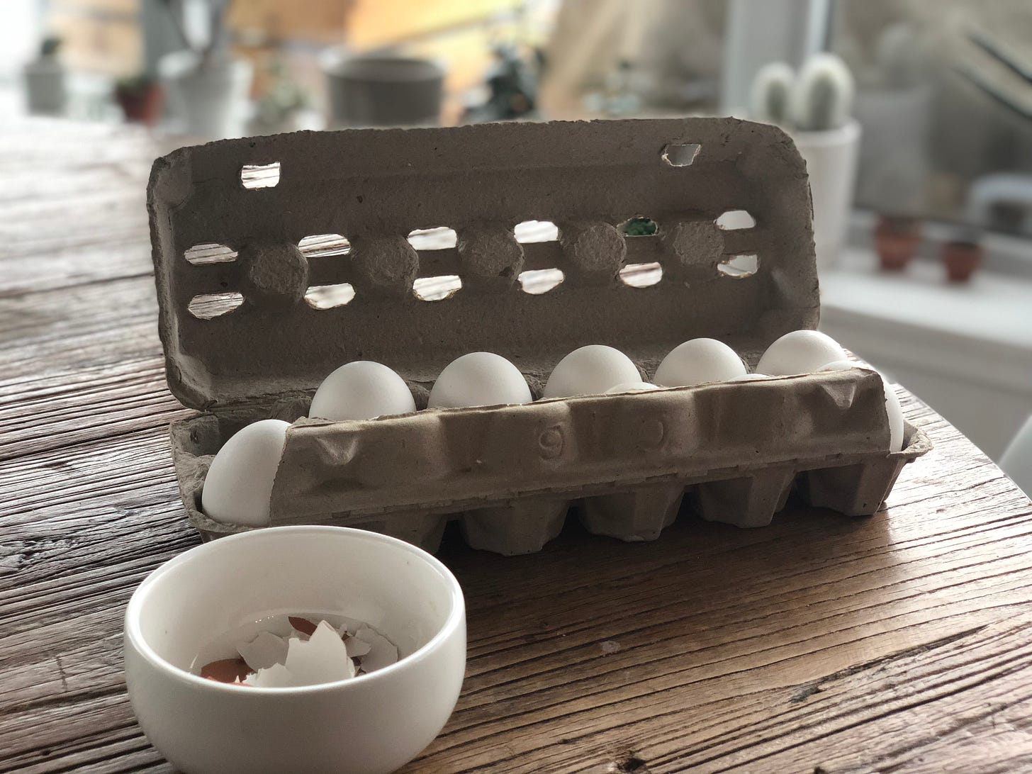 A carton of eggs and a small bowl of eggshells