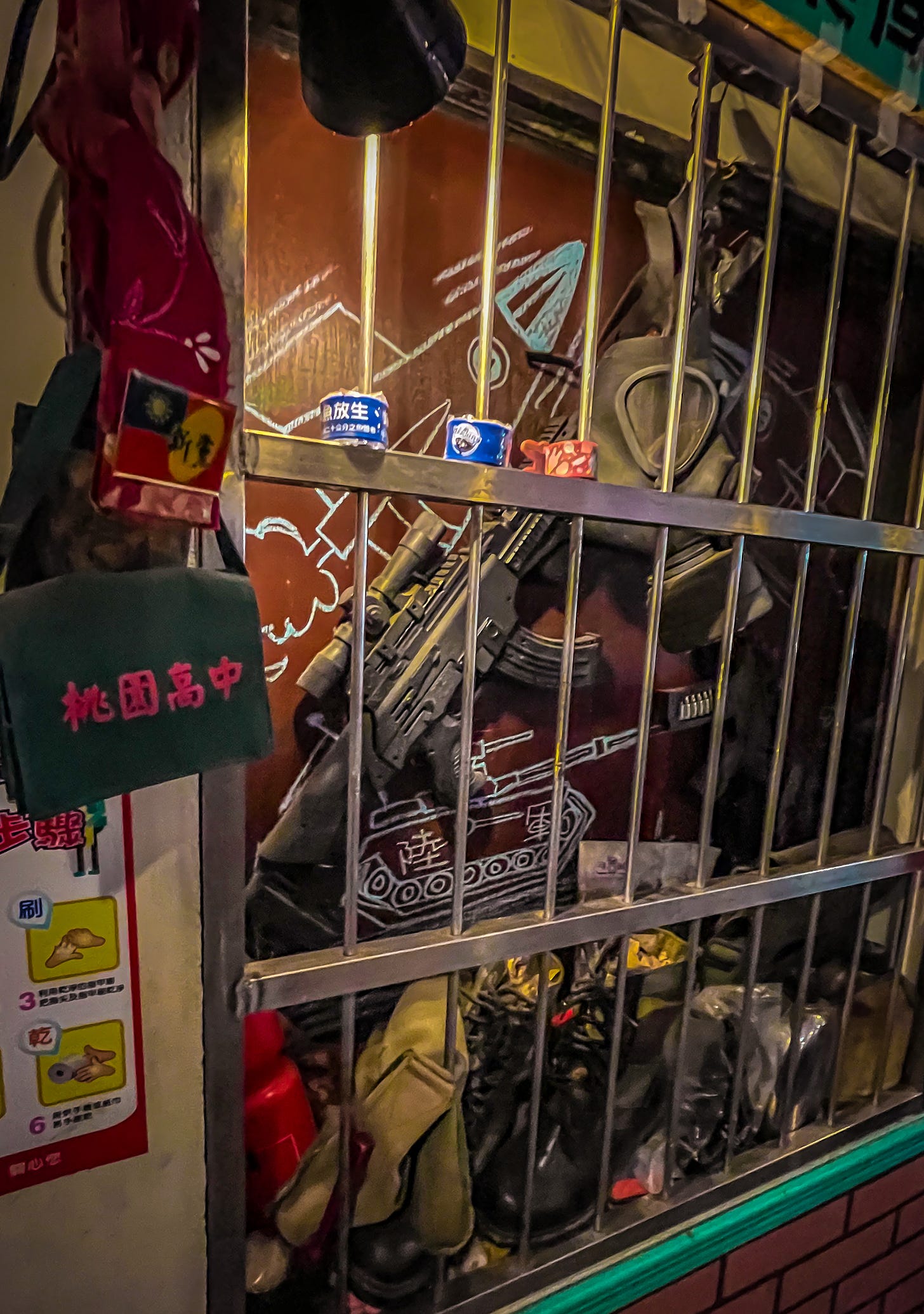 A Taiwanese army-issue machine gun and gas mask hang in a locked display case in the dining room of Army Diner in Taoyuan