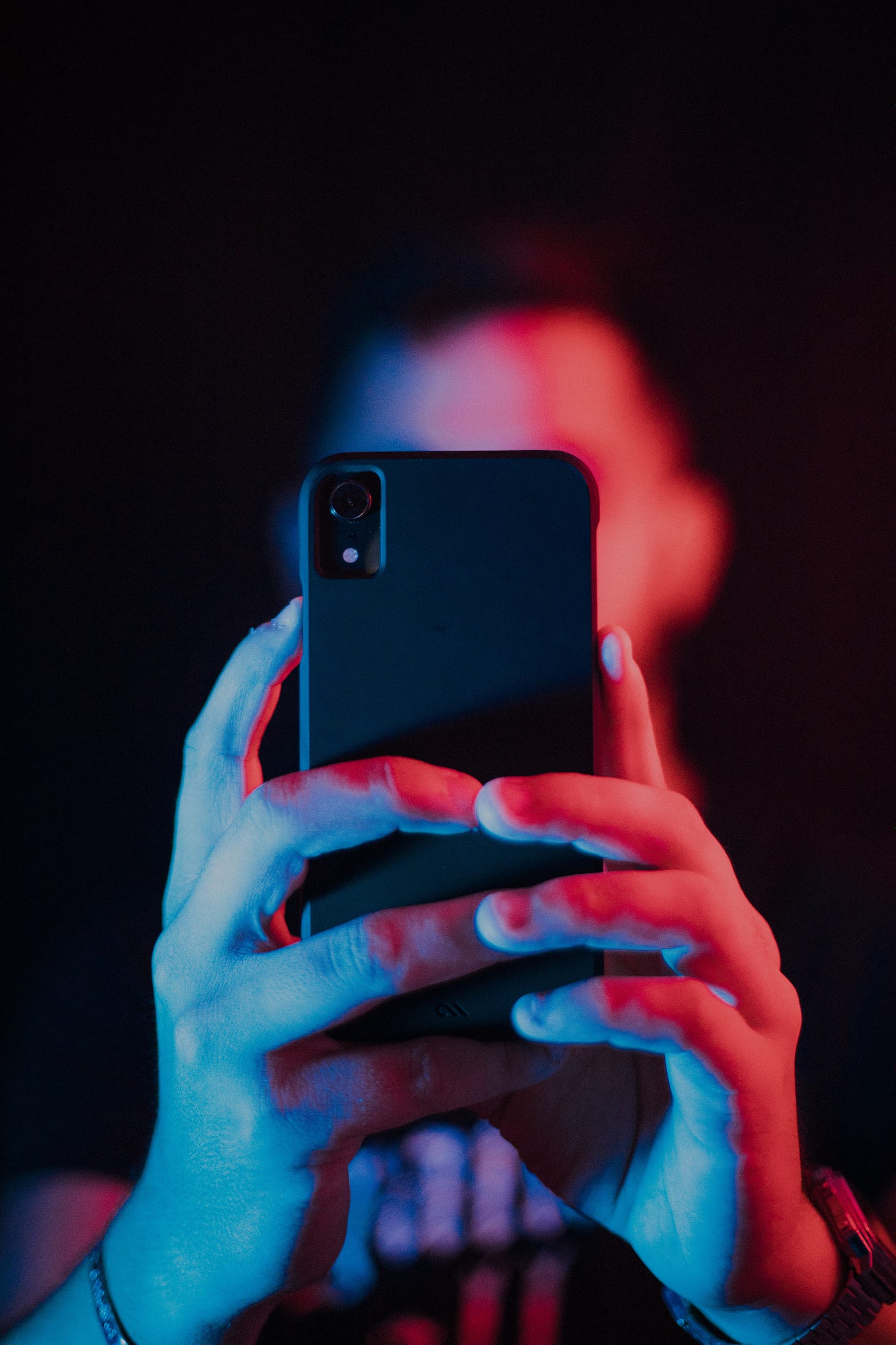 Photo of a person with a mobile phone in front of their face.