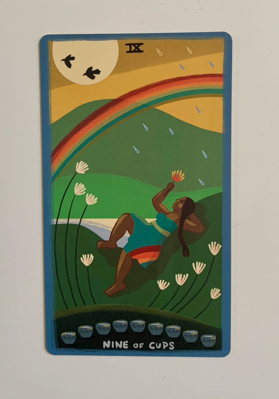 a native woman reclines on a hillside.she holds a flower. above there is a rainbow and rain and birds and sun. there are 9 white flowers and 9 cups at the bottom of the cards