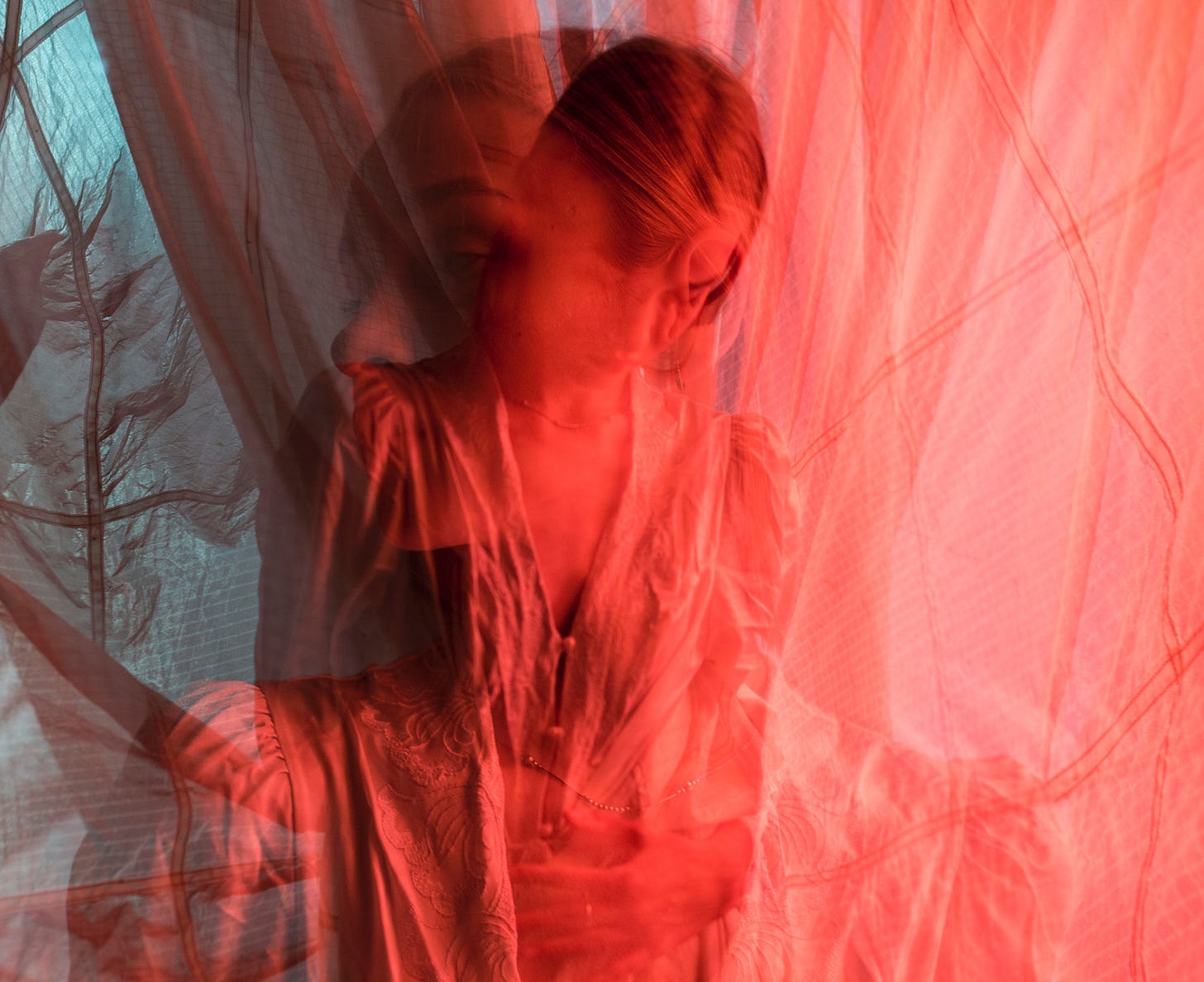 Woman behind sheer red curtain hiding