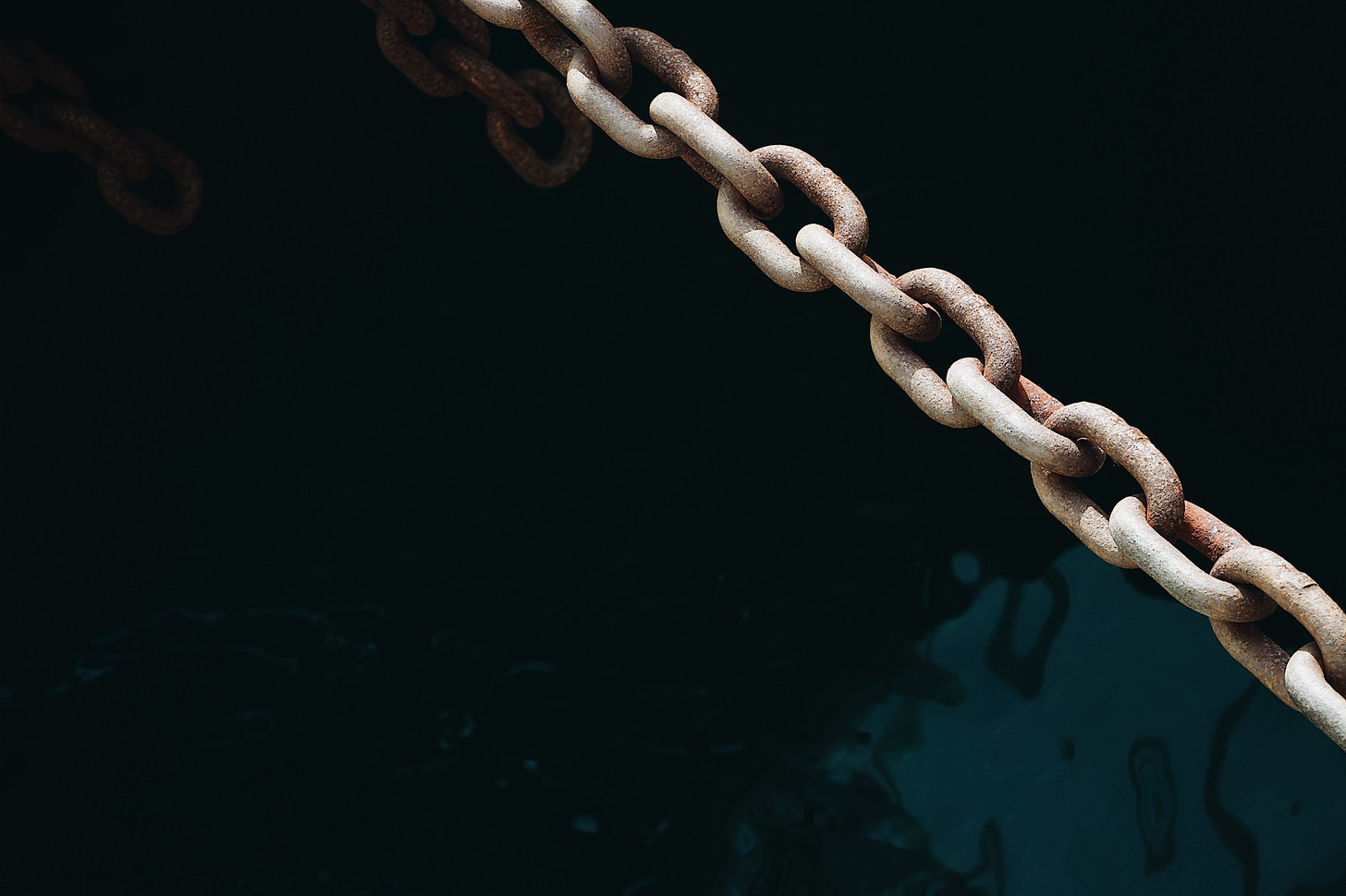 A rusted chain over deep dark water
