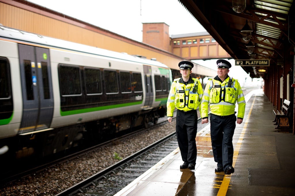 Two police officers patrol a UK railway station