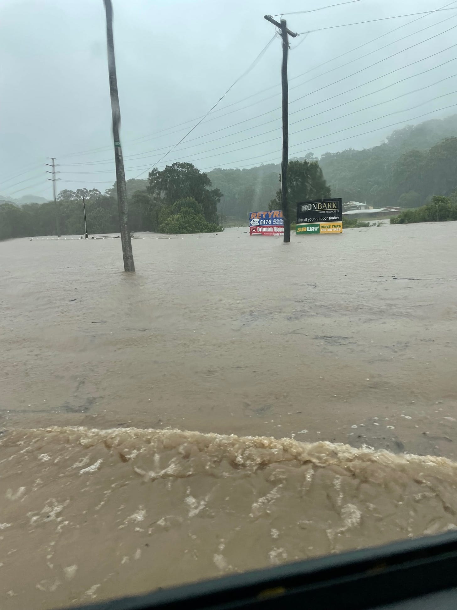 A photo of flood waters on the Sunshine Coast. The water goes up to the billboards on the side of the road