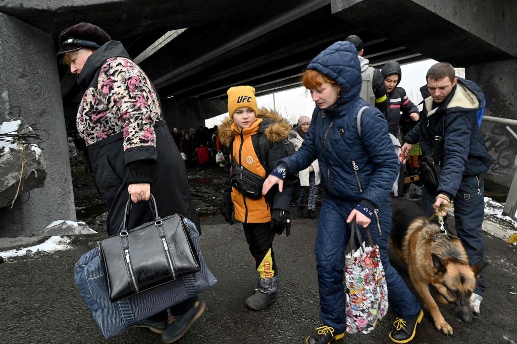 People cross a destroyed bridge as they evacuate the city of Irpin.