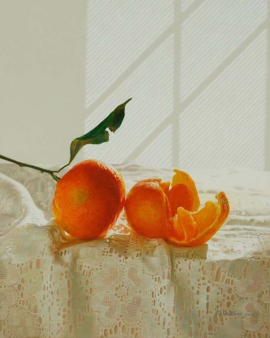 Two oranges rest on a lace tablecloth.