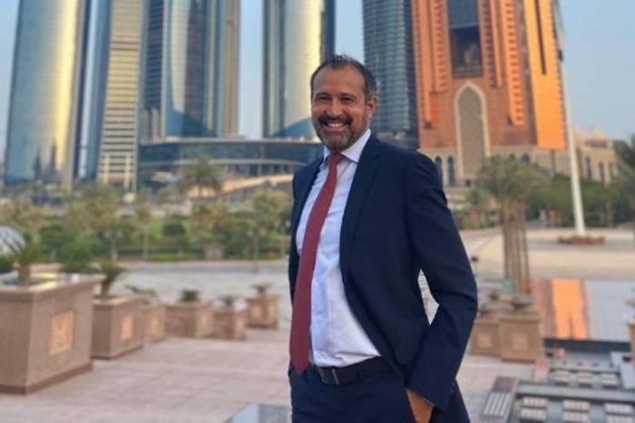 Orral Nadjari standing in a suit with a Dubai cityscape in the background