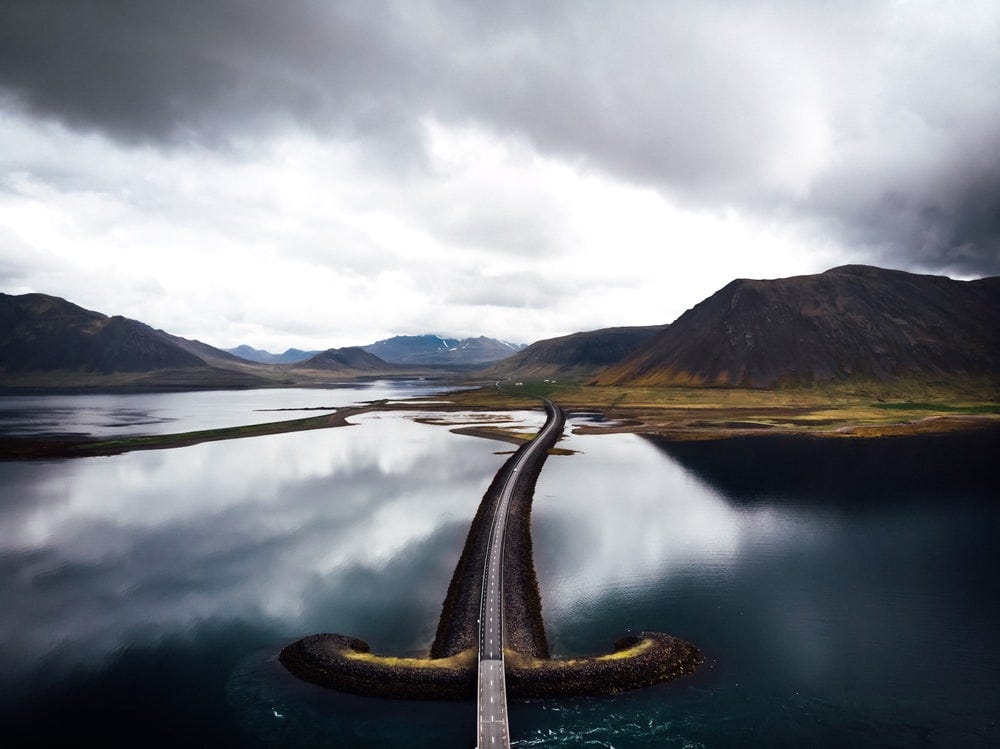 asphalt road in the middle of bodies of water