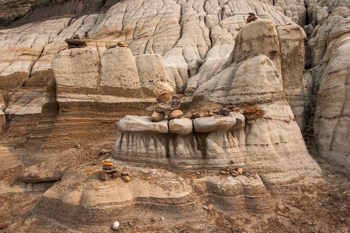 rockpiles and rock creatures sit atop hoodoos and ledges of sandstone emerging like an altar from the striped earth