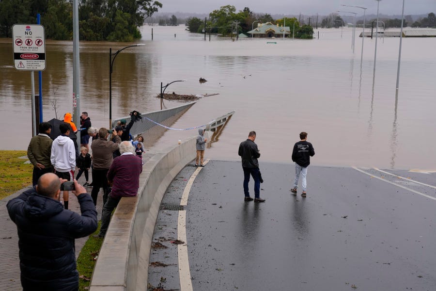 People look at the flooded Windsor Bridge at Windsor on the outskirts of Sydney, Australia, Tuesday, July 5, 2022. Hundreds of homes have been inundated in and around Australia’s largest city in a flood emergency that was impacting 50,000 people, officials said Tuesday.