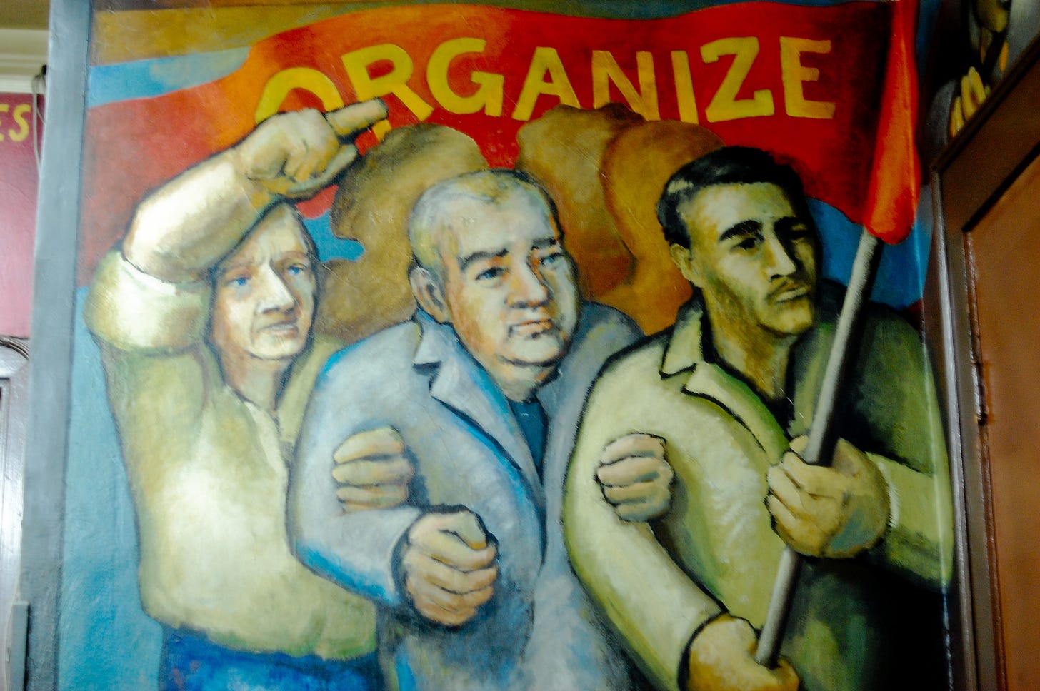 three workers, arm in arm, hold a banner reading “Organize”. detail of the Chicago UE Hall mural