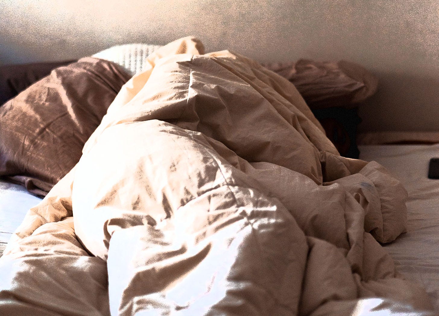 a person in bed and completely covered by a blanket