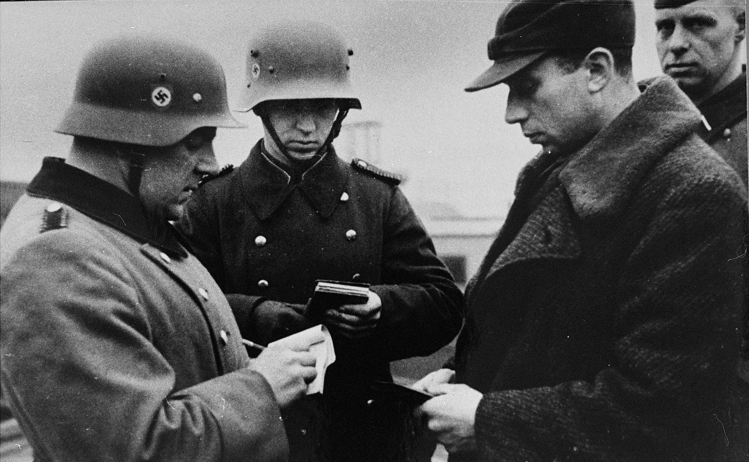 German police or soldiers check the identification papers of a Jew in ...