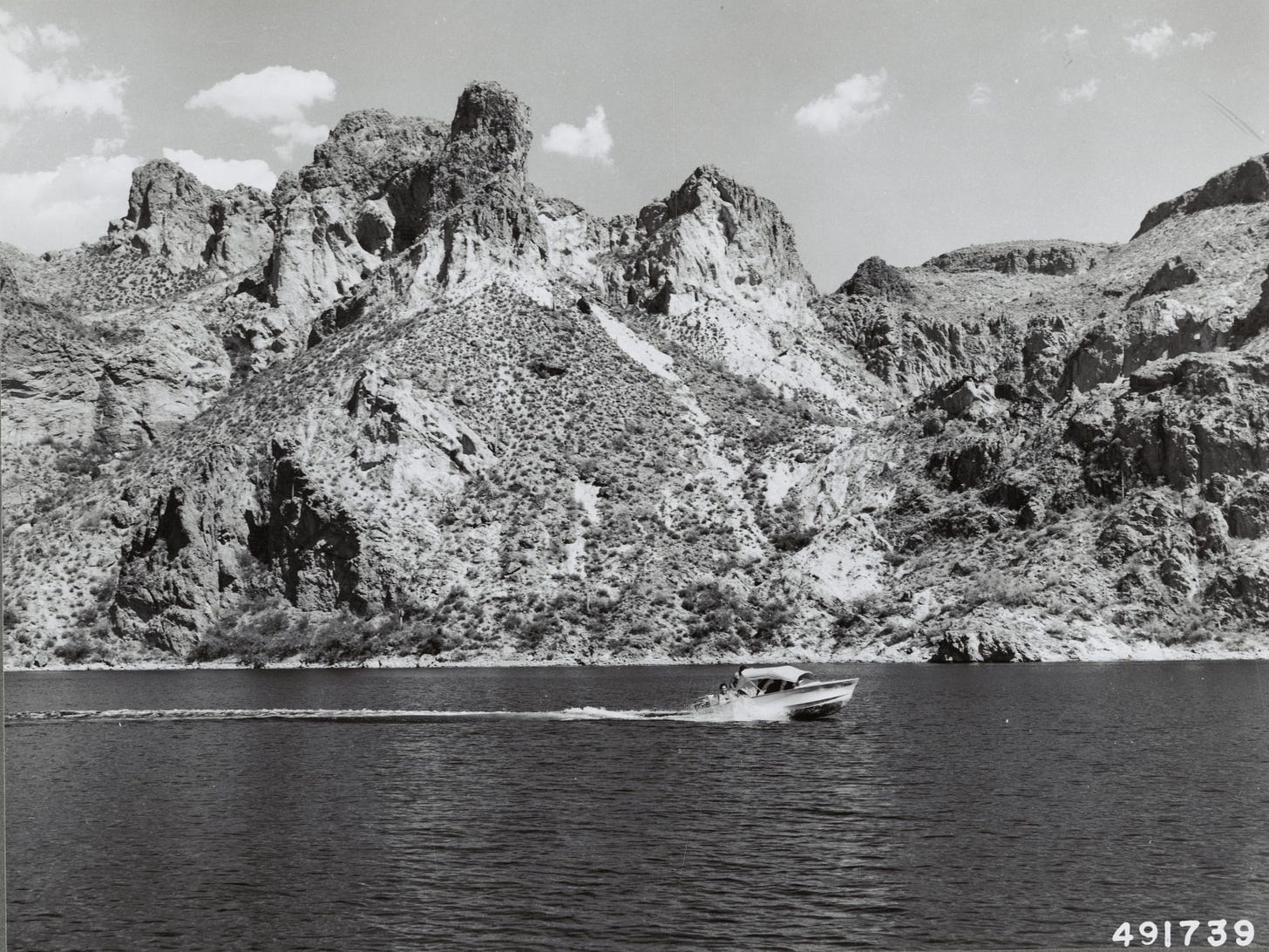 boat in a lake with rugged rocky shoreline in the background
