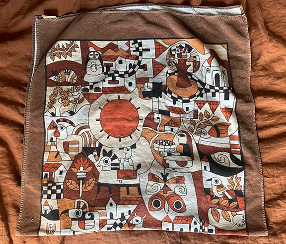 Towel with decorate images in Mayan style, mostly brown, orange, black, yellow, and cream.
