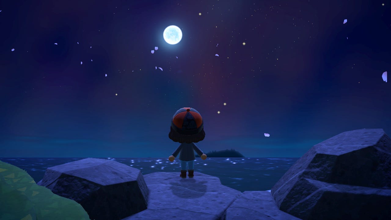 Screenshot from Animal Crossing: New Horizons. A cartoon person's back is to us while she faces a full moon over the ocean, and pink cherry blossom petals float across a starry sky.