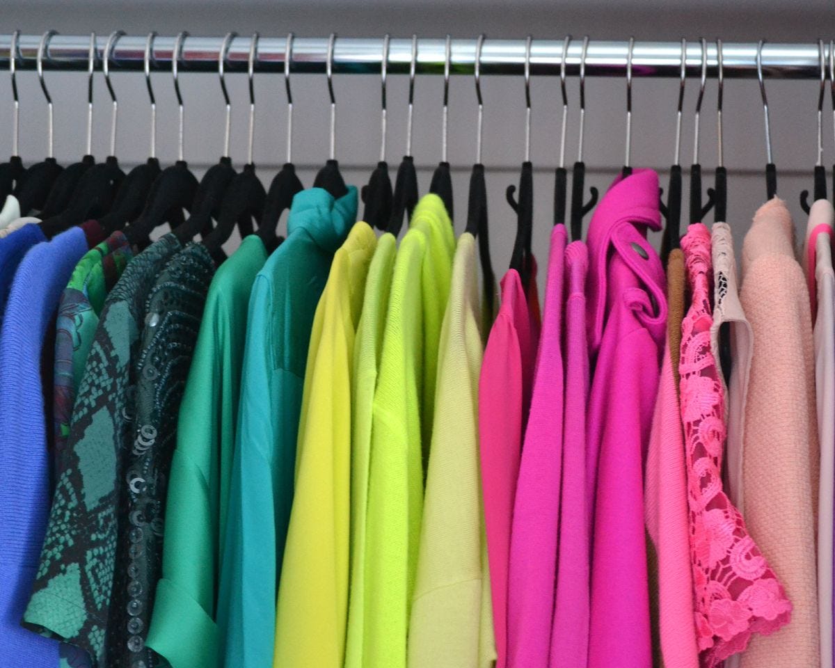 Closet with clothing arranged by color.