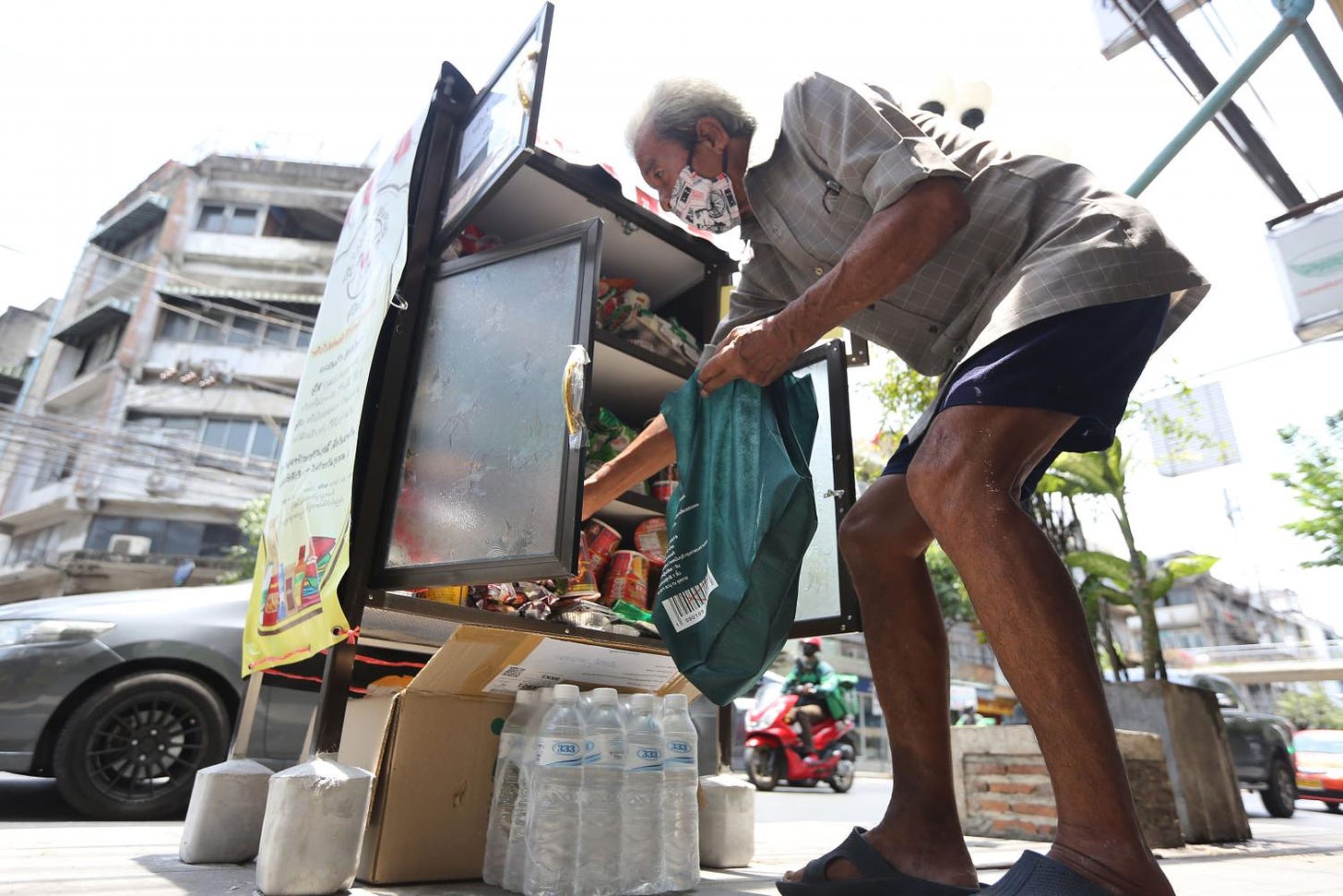 A man selects items he needs from a roadside cupboard on Sukhumvit 71.  Wichan Charoenkiatpakul